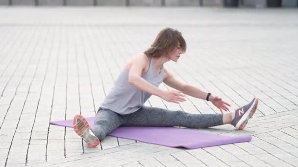 Ejercicio de mujer adulta en forma delgada en un entrenamiento al aire libre solo. Atardecer de verano retratos matutinos en acción en calles europeas con espacio para el texto — Vídeos de Stock