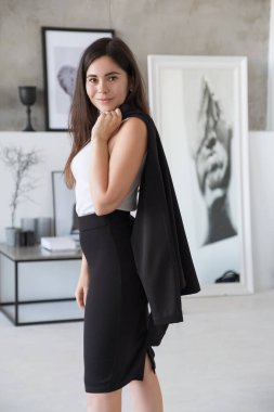 Beyaz bluzlu esmer beyaz kadın ve siyah etekli iş elbisesi evde. Neşeli iş portresi.