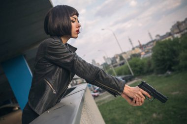 Güzel esmer, seksi ajan (katil ya da polis) Deri ceketli ve kot pantolonlu bir kadın, birinin peşinden koşuyor, onu park yerinde yakalamak için..