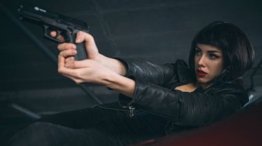 Güzel esmer, seksi ajan (katil ya da polis) Deri ceketli ve kot pantolonlu bir kadın, birinin peşinden koşuyor, onu park yerinde yakalamak için..