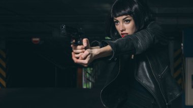 Güzel esmer, seksi ajan (katil ya da polis) Deri ceketli ve kot pantolonlu bir kadın, birinin peşinden koşuyor, onu park yerinde yakalamak için..