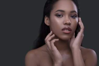 Koyu tenli, genç ve güzel bir kadın. Tarafsız yeşil bir arka planda şehvetle poz veriyor. Çıplak makyajlı kusursuz bir cilt. Metin için yer olan cilt bakım konsepti portresiName.