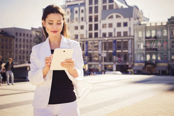 Beautiful brunette business woman in white suit working on a tab — Stock Photo, Image