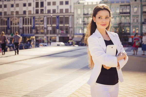 Beautiful brunette business woman in white suit working on a tab — Stock Photo, Image