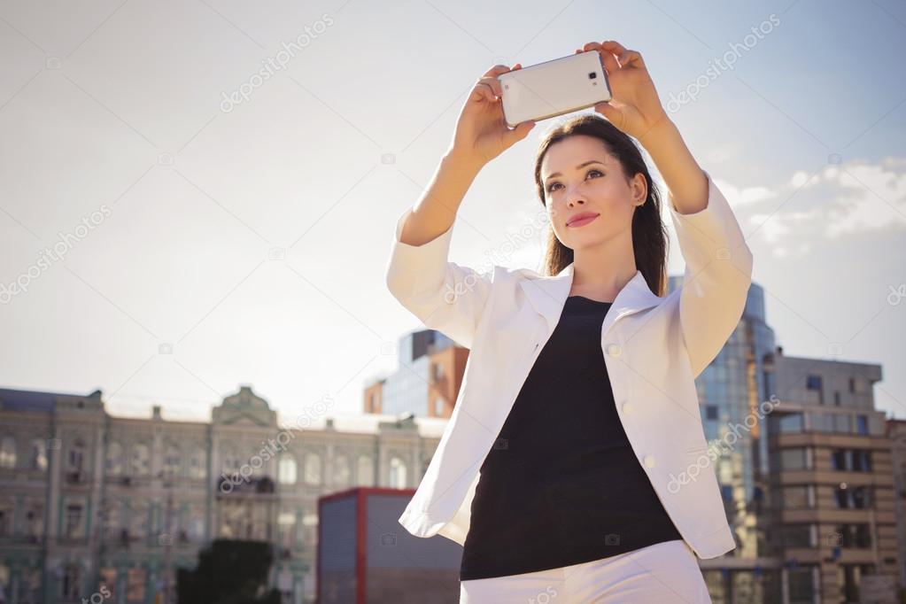 Beautiful brunette business woman in white suit photographing se