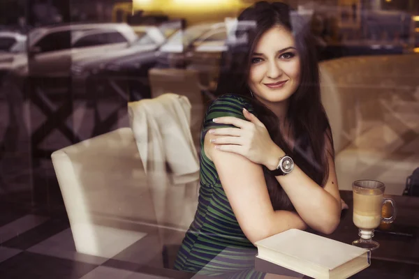 Brunett kvinna sitter på café läsa boken, studerar och dricka kaffe och prata i telefon. kopia utrymme — Stockfoto