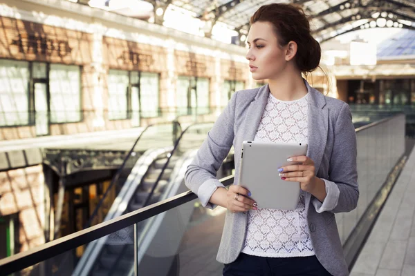 Belle femme brune en veste grise, pantalon foncé et chemisier blanc avec tablette à l'extérieur. Espace de copie — Photo