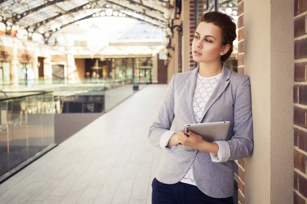 Beautiful brunette woman in grey jacket, dark trousers and white blouse with tablet outdoors. Copy Space — Stock Photo, Image