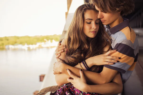 Young couple hugging in the summer daylight on a bridge construc — Stock Photo, Image