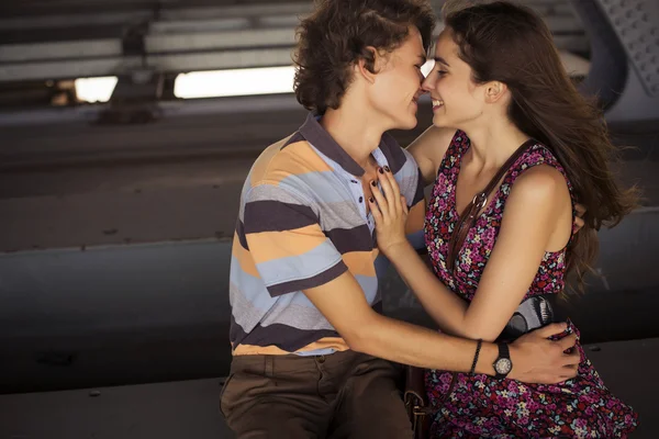 Ungt par kysser i sommaren dagsljus på en bro entreprenad — Stockfoto