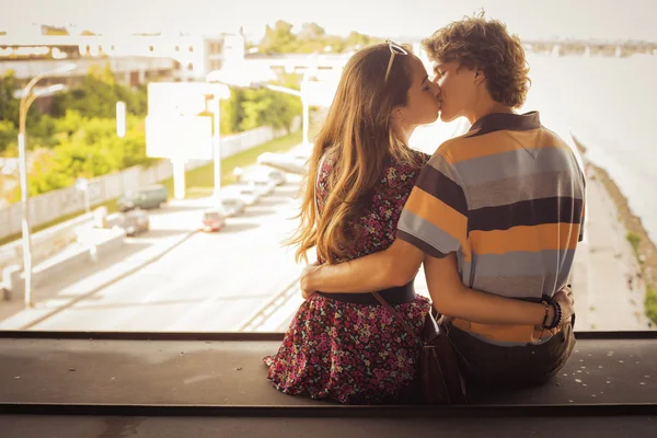 Casal jovem beijando na luz do dia de verão em uma construção de ponte — Fotografia de Stock