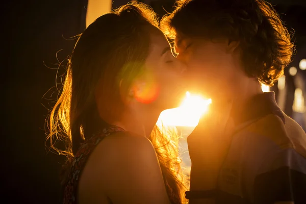 Young couple kissing in the flares of sunset light on a bridge c — Stock Photo, Image