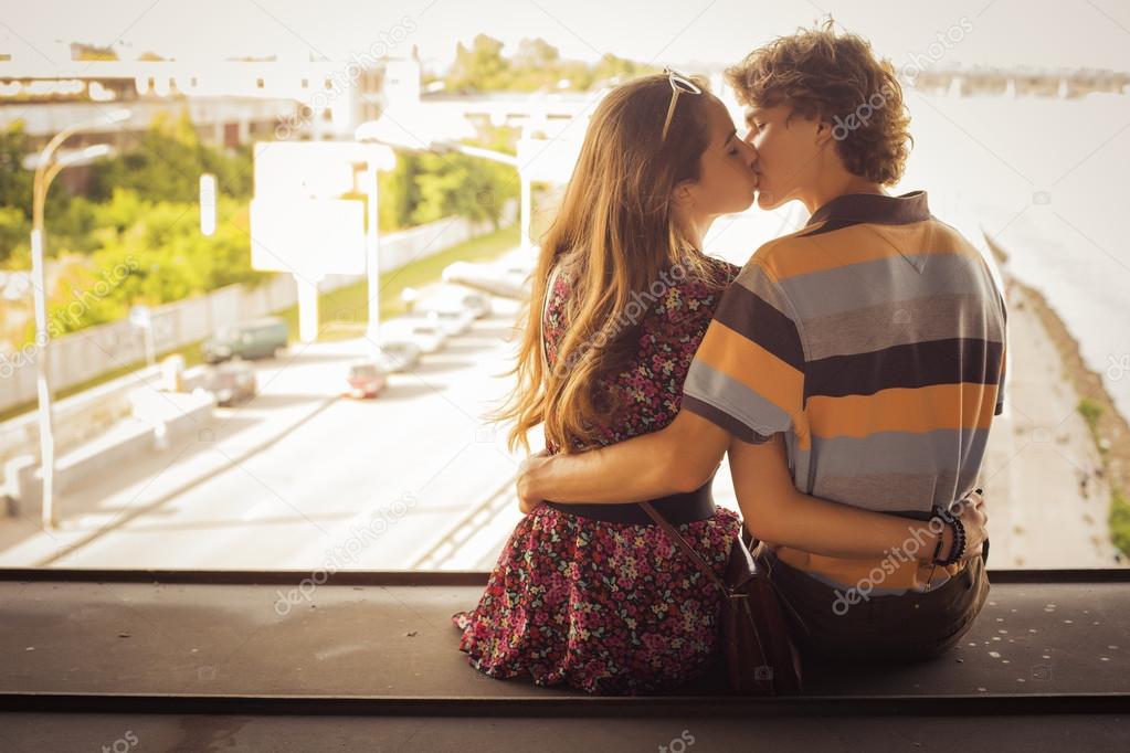 Young couple kissing in the summer daylight on a bridge construc