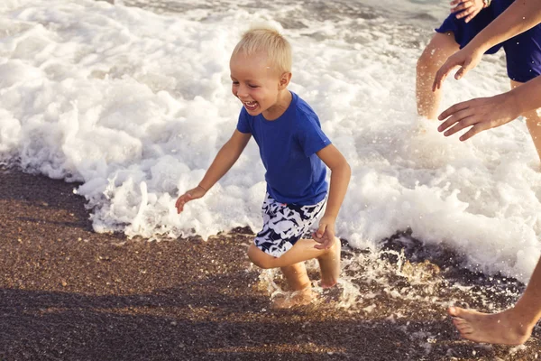 Petit garçon jouant dans l'eau de mer sur une plage. espace de copie — Photo