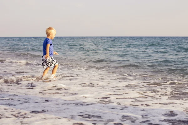 Niño jugando en el agua de mar en una playa. espacio de copia — Foto de Stock