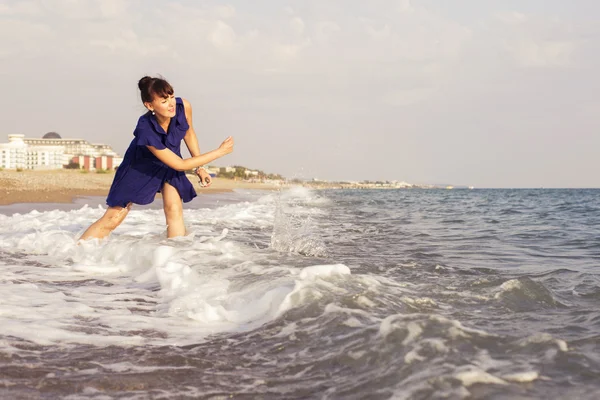 Женщина бросает камни на песчаном берегу у моря, глядя на — стоковое фото