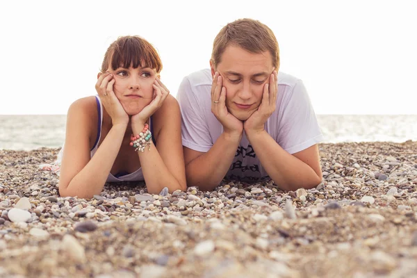 Couple sitting on a  sand seashore near sea looking sad, relaxin — Stock Photo, Image