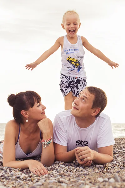 Familia sentada en una playa de arena cerca del mar mirando a cada uno de los demás — Foto de Stock