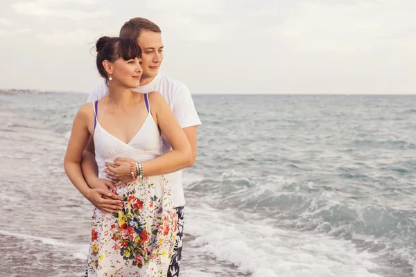 Coppia in piedi su una spiaggia di sabbia vicino al mare guardando l'acqua — Foto Stock