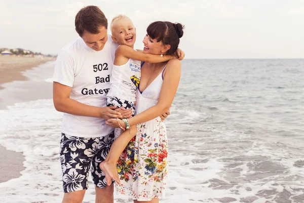 Famille debout sur un rivage de sable près de la mer jouant dans la mer — Photo