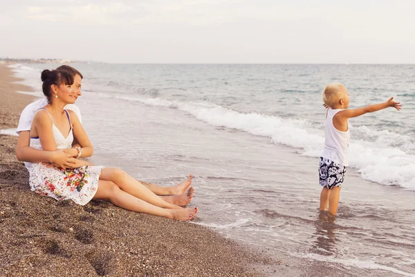 Familia sentada en una playa de arena cerca del mar mirando a cada uno de los demás — Foto de Stock