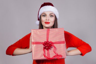Esmer kadın kırmızı elbise ve Santa şapka hediye tutarak ve kamera arıyorum