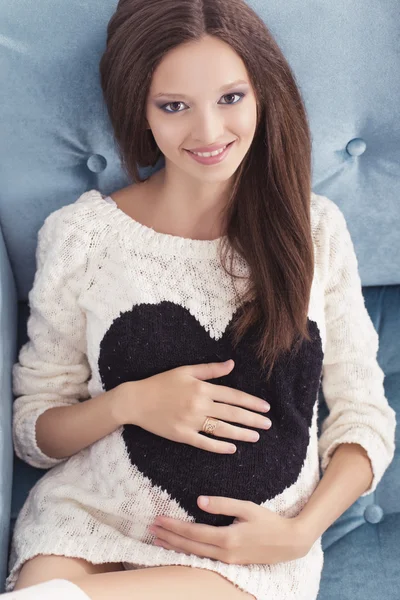 Beautiful brunette woman on a 7th month pregnancy in white sweat — Stock Photo, Image