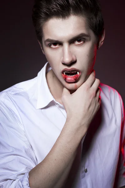 Young sexy man dracula vampire with red eyes and fangs, mouth co Royalty Free Stock Photos