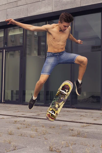 Giovane ragazzo biondo che salta sullo skateboard in abito casual in u — Foto Stock