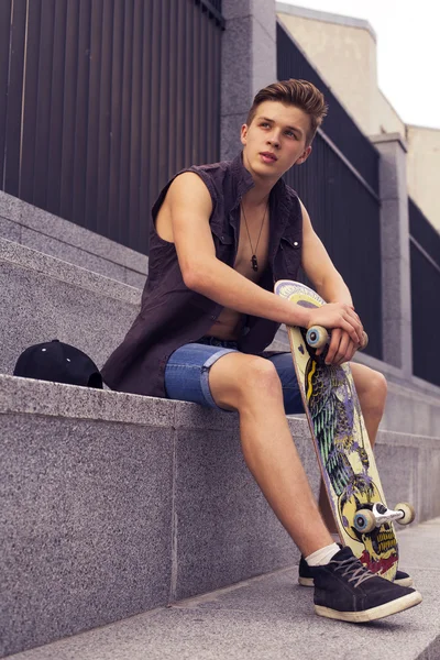 Young blonde guy on skateboard in casual outfit in the urban cit — Stock Photo, Image