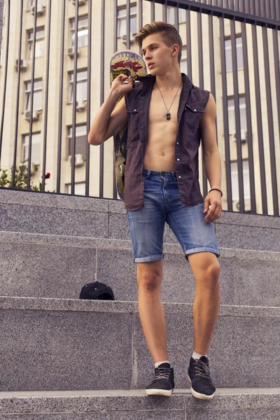 Young blonde guy on skateboard in casual outfit in the urban cit — Stock Photo, Image