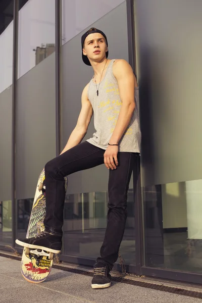 Junger blonder Kerl auf dem Skateboard in lässigem Outfit in der Stadt — Stockfoto