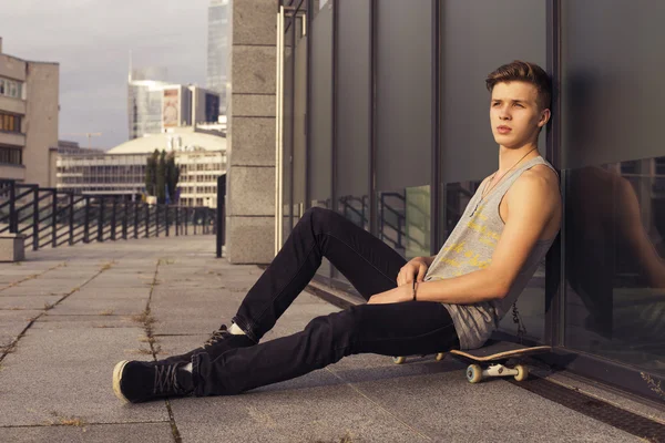 Young blonde guy on skateboard in casual outfit in the urban cit — Stock Photo, Image