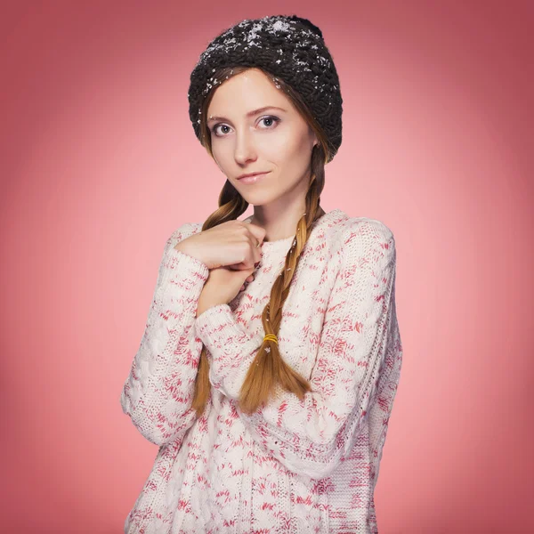 Красива руда жінка в зимовому вбранні: теплий светр, шарф і капелюх зі снігом на всьому протязі. Ізольовані на рожево-червоному — стокове фото