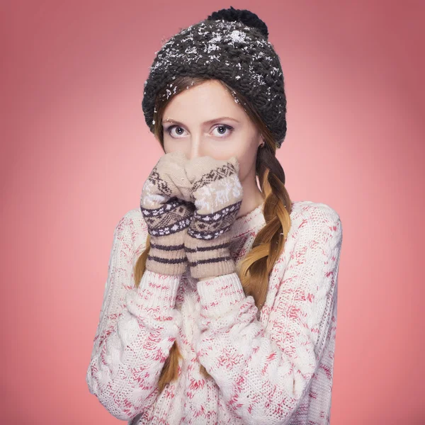 Красива руда жінка в зимовому вбранні: теплий светр, шарф і капелюх зі снігом на всьому протязі. Ізольовані на рожево-червоному — стокове фото