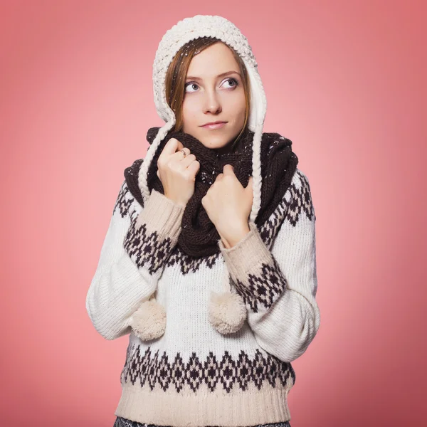 Schöne rothaarige Frau im winterlichen Outfit: warmer Pullover, Schal und Mütze mit Schnee über dem ganzen Körper. isoliert auf rosa rot — Stockfoto