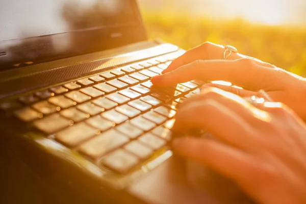 Woman typing on a laptop keyboard in a warm sunny day outdoors. — Stock Photo, Image