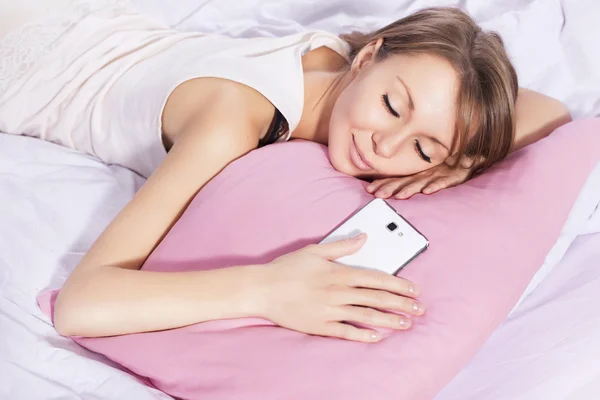 Hermosa mujer rubia durmiendo con un teléfono en la mano, esperando —  Fotos de Stock