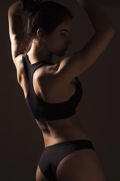 Sexy slim fit vrouw lichaam. Gespierd terug. Sportkleding. Donkere backgro — Stockfoto