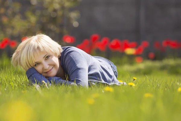 Blondynka piękna starszyznę starszy kobieta relaksujący na trawie w tył — Zdjęcie stockowe