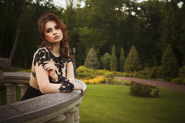 Beautiful sexy brunette luxury rich woman standing on a balcony — Stock Photo, Image