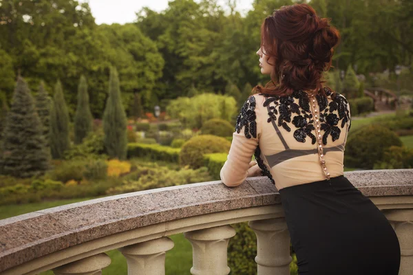 Beautiful sexy brunette luxury rich woman standing on a balcony — Stock Photo, Image