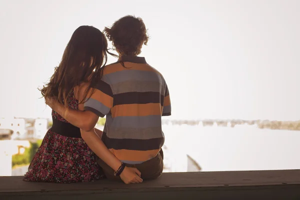 Jovem casal abraçando a luz do dia de verão em uma construção de ponte — Fotografia de Stock