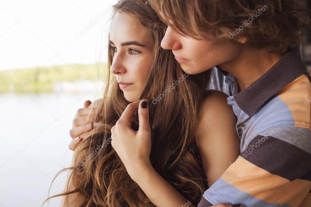 Young couple hugging in the summer daylight on a bridge construc