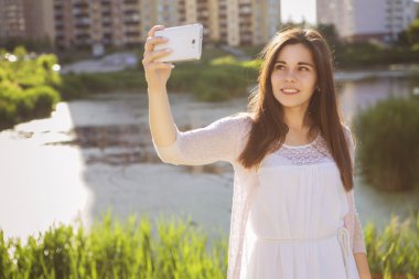 Young beautiful brunette girl in white dress photographing herse clipart