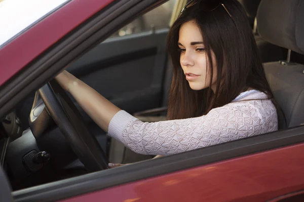 Młoda piękna brunetka kaukaski kobieta jazdy czerwony samochód. suma — Zdjęcie stockowe
