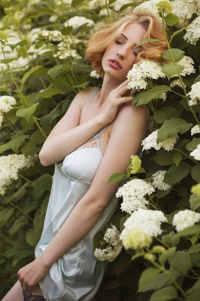 Bella donna bionda con capelli ricci corti bob, trucco delicato e labbra rosse in abito corto verde al parco. Moda sensuale posa sul tramonto estivo. All'aperto — Foto Stock