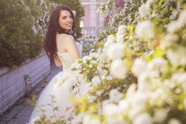 Mooie brunette vrouw bruid in een tuin park in witte bruiloft — Stockfoto