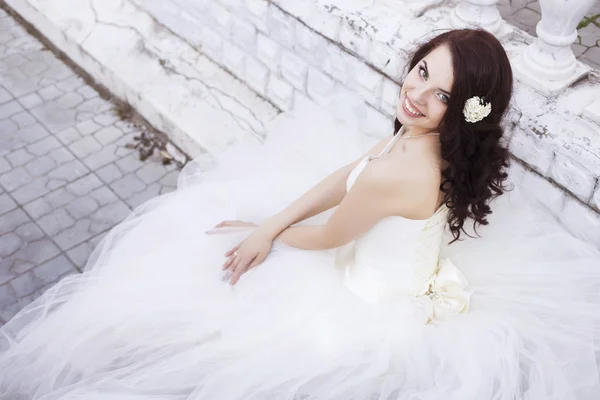 Mooie brunette vrouw bruid in een tuin park in witte bruiloft — Stockfoto