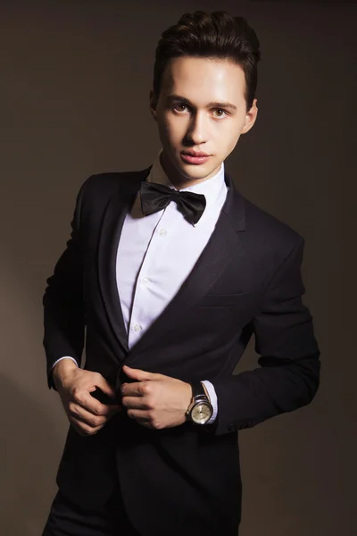 Ung vacker brunett macho affärsman i svart kostym och rosett — Stockfoto
